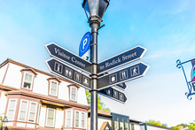 City Street Signs Showing Directions In Downtown Village In Summer During Sunset