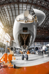 Wall Mural - A large passenger aircraft on the service in the aviation hangar view the nose and radar under the hood, the front chassis riser.