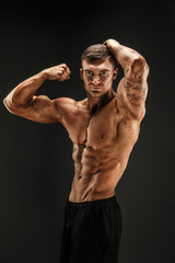 Wall Mural - Very brawny guy bodybuilder posing. Beautiful sporty guy male power. Fitness muscled man in studio. Dark background.