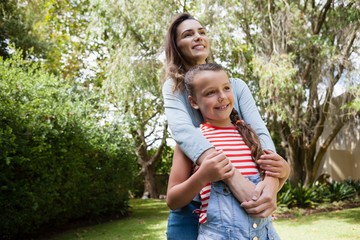 Wall Mural - Smiling woman and daughter standing against trees