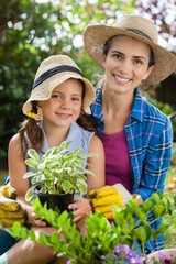 Wall Mural - Portrait of smiling mother and daughter with potted plants