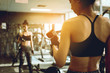 © wutzkoh - Asian woman lifting dumbbell in front of mirror in fitness gym.