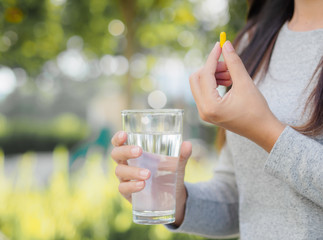 Close up of woman taking in pill with bokeh background. Health care and medical concept.