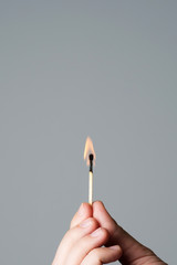 hand holding a burning matchstick