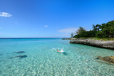Fototapeta Most - Tourist swimming in turquoise waters of the Caribbean sea on the wild noon coast of Cuba