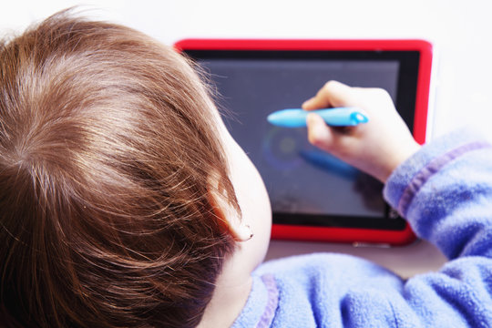 Baby girl drawing on the  graphics tablet. The young designer. (Humorous picture)