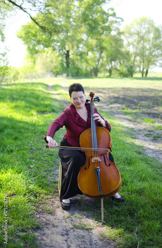 Zdjęcie XXL Dorosła muzyk kobieta bawić się na violoncello outdoors. Nauczyciel muzyki gra na wiolonczeli