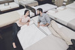 © VadimGuzhva - The couple came to a large mattress store to choose their own mattress. They lay down on one of them