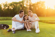 © VadimGuzhva - The family rests after playing golf and look at the smartphone screen together. They are happy and smiling