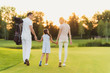 © VadimGuzhva - The family is walking along the golf course. Mother and father holding hands of their daughter