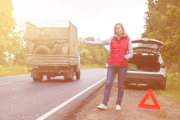 Wall Mural - Frustrated woman driver near a broken car. A car on a country road, a woman catches a ride