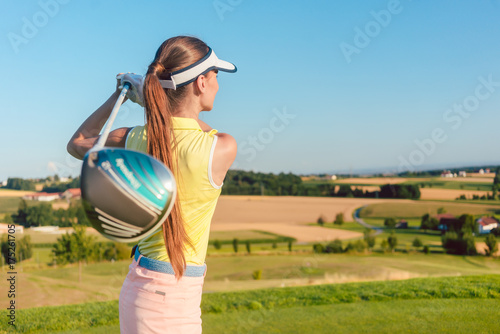 Young Woman Holding A Driver Club Behind Her Back During