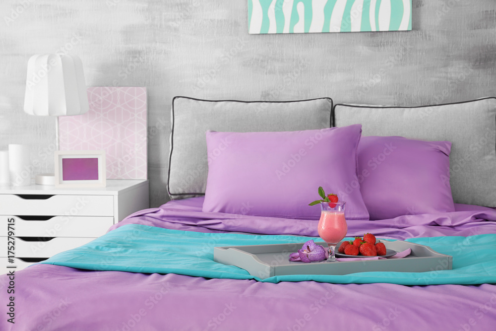 Lilac accent in modern interior. Tray with tasty breakfast on bed