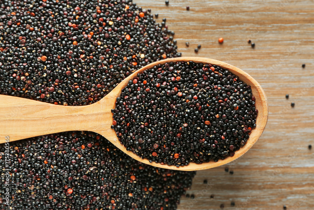 Spoon with quinoa seeds on wooden table