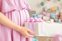 Pregnant Woman Holding Gift At Baby Shower Party Indoors