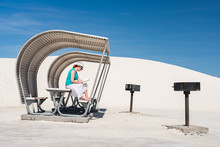 Woman Reading Book In Stark Metal Shelter At White Sands National Monument New Mexico