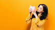 © Tierney - Young woman with a piggy bank on a yellow background