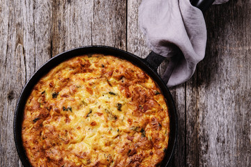 Wall Mural - Zucchini, bacon and cheese casserole or gratin in cast-iron pan on vintage wooden table. Selective focus 