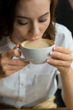 Fototapeta  - Close up of young beautiful woman drinking coffee in a cafe
