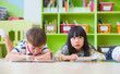 © weedezign - Two kid lay down on floor and reading tale book in preschool library,Kindergarten school education concept