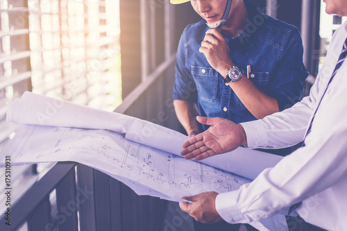 Fotografía contractor and engineer with blueprints discuss at a modern construction site, Architecture and Engineering concept