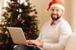 © zinkevych - Charming man in Santa hat posing with laptop