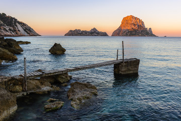 Small wooden pier in Cala d'Hort beach, Es Vedra as background, Ibiza island, Spain