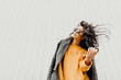 © vitleo - Portrait of stylish modern young curly woman in coat sunglasses. She smile at camera on the street and looks happy. Truly emotions.