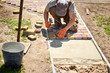 © serhiilysenko - Laying Paving Slabs by mosaic close-up. Road Paving, construction. Repairing sidewalk. Worker laying stone paving slab. Laying colored tiles in city park (garden). Hand fixed tessellated sidewalk tile