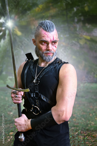 Cosplayer dressed as character Geralt from Rivia from game Witcher, poses durin Poster