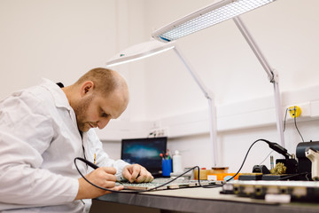 Technician fixing motherboard by soldering