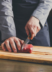 Sticker - Chef cutting filet mignon on wooden board at restaurant kitchen