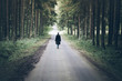 © Christian Horz - young blonde caucasian woman walking on narrow road through dark forest