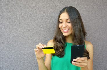 Portrait of a young smiling woman buying online with a smartphone outdoors