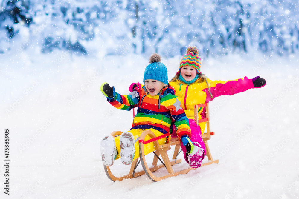 Kids play in snow. Winter sleigh ride for children - obrazy, fototapety, plakaty 