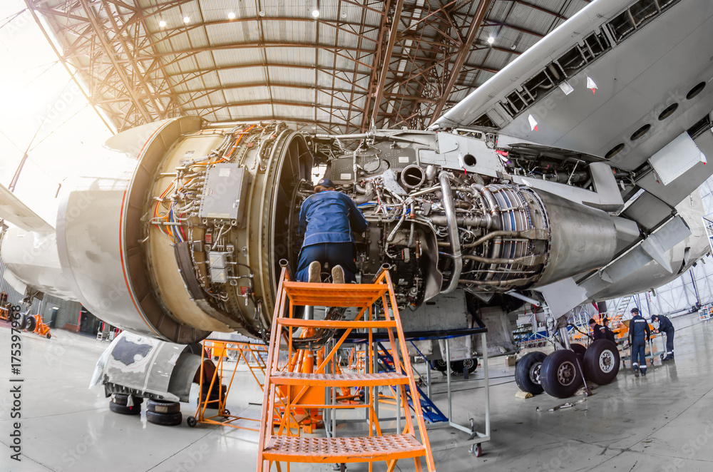 Specialist mechanic repairs the maintenance of a large engine of a passenger aircraft in a hangar. - obrazy, fototapety, plakaty 