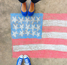 Feet In Blue Sneakers And Flats Standing Over A Drawn Chalk American Flag