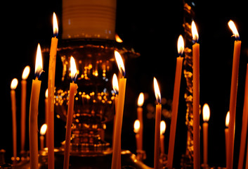 Burning wax candles in Christian church as a symbol of faith in black background, close up