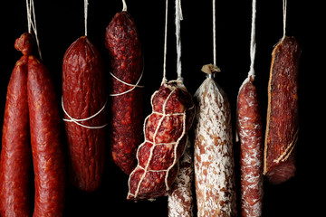 Wall Mural - Delicious sausages hanging on dark background