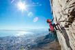 © MickyWiswedel/Stocksy - Female rock climber climbing a sheer cliff overlooking a city
