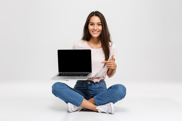 Portrait of a cheerful young asian girl pointing finger