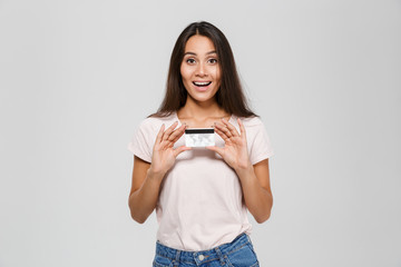 Wall Mural - Portrait of an excited happy asian woman holding credit card