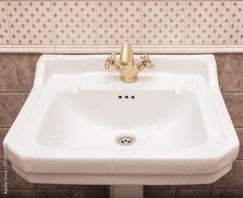 White Ceramic Sink With Bronze Faucet Against The Wall With Tiles