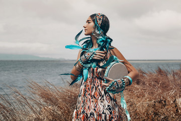 Poster - attractive young woman in ethnical costume on a field at sea