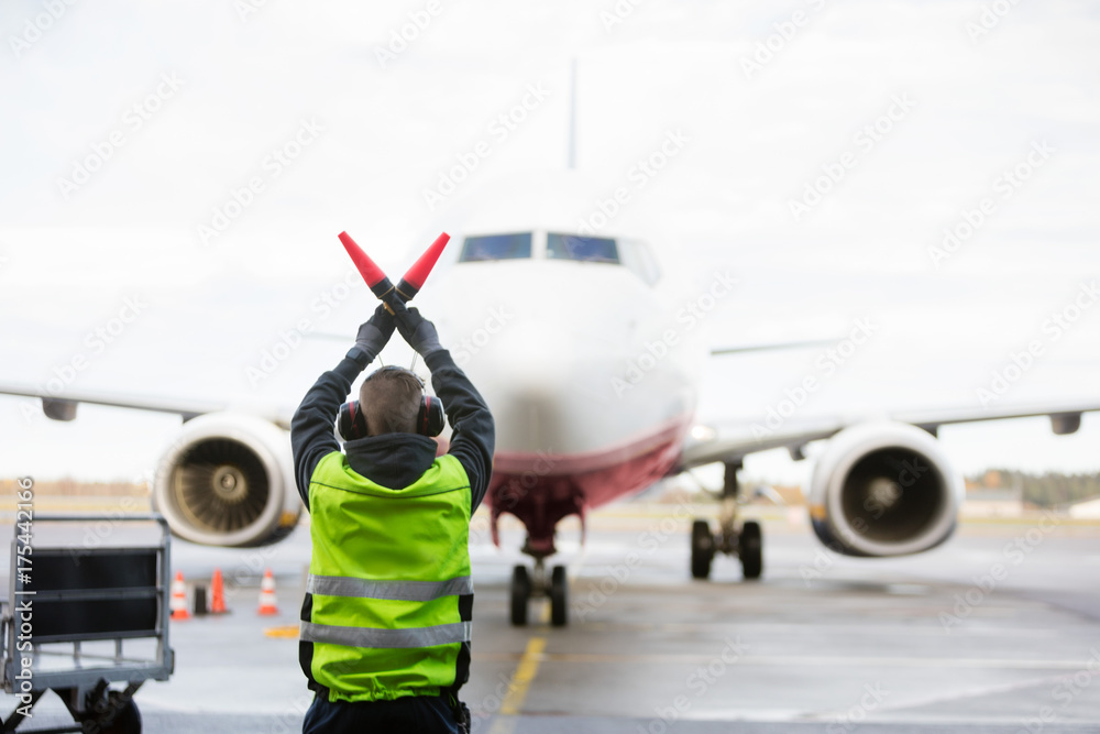 Ground Worker Signaling To Airplane On Runway - obrazy, fototapety, plakaty 