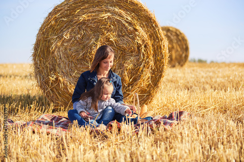 Fotomural Happy mother and 2 year old girl next to hay bales in harvested field