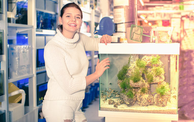 Wall Mural - Girl standing next to pleasing aquarium with striped tropical fish