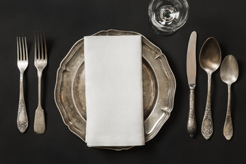 Vintage dish with silverware for lunch on black background. Table place setting.