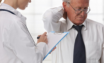 Doctor and senior male patient suffering from back pain during medical exam.