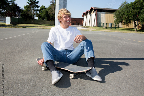 Plakat ładny nastolatek blond chłopiec siedzi na deskorolce